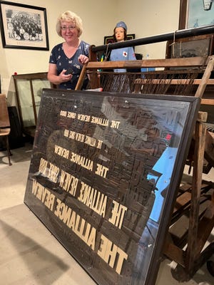 Karen Perone, president of the Alliance Historical Society, stands behind a large collage of block print letters that was on display at The Alliance Review offices for more than 40 years. It is now housed in the Alliance History Mini Museum.