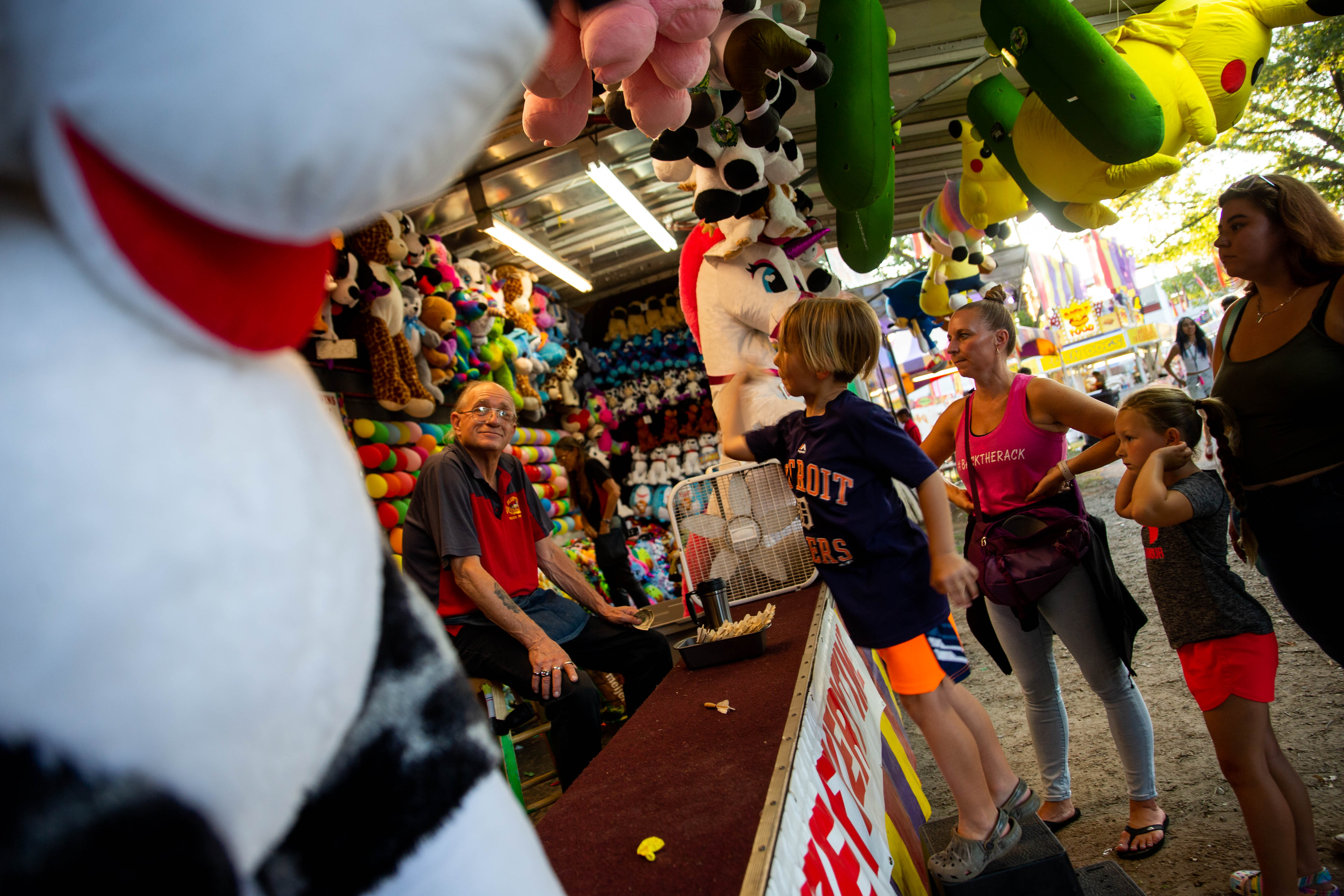 A young fair-goer throws darts as they play games on the midway Wednesday, July 27, 2022, at the Ottawa County Fairgrounds.