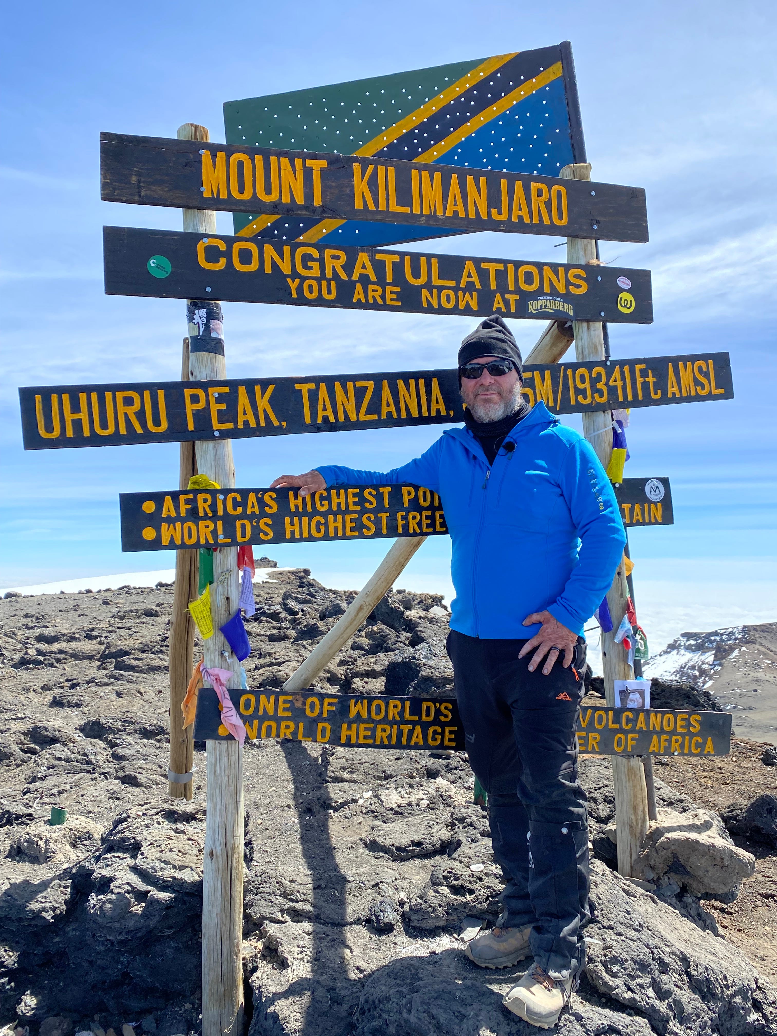 Jason Nelson stands next to the trail marker for Uhuru Peak.