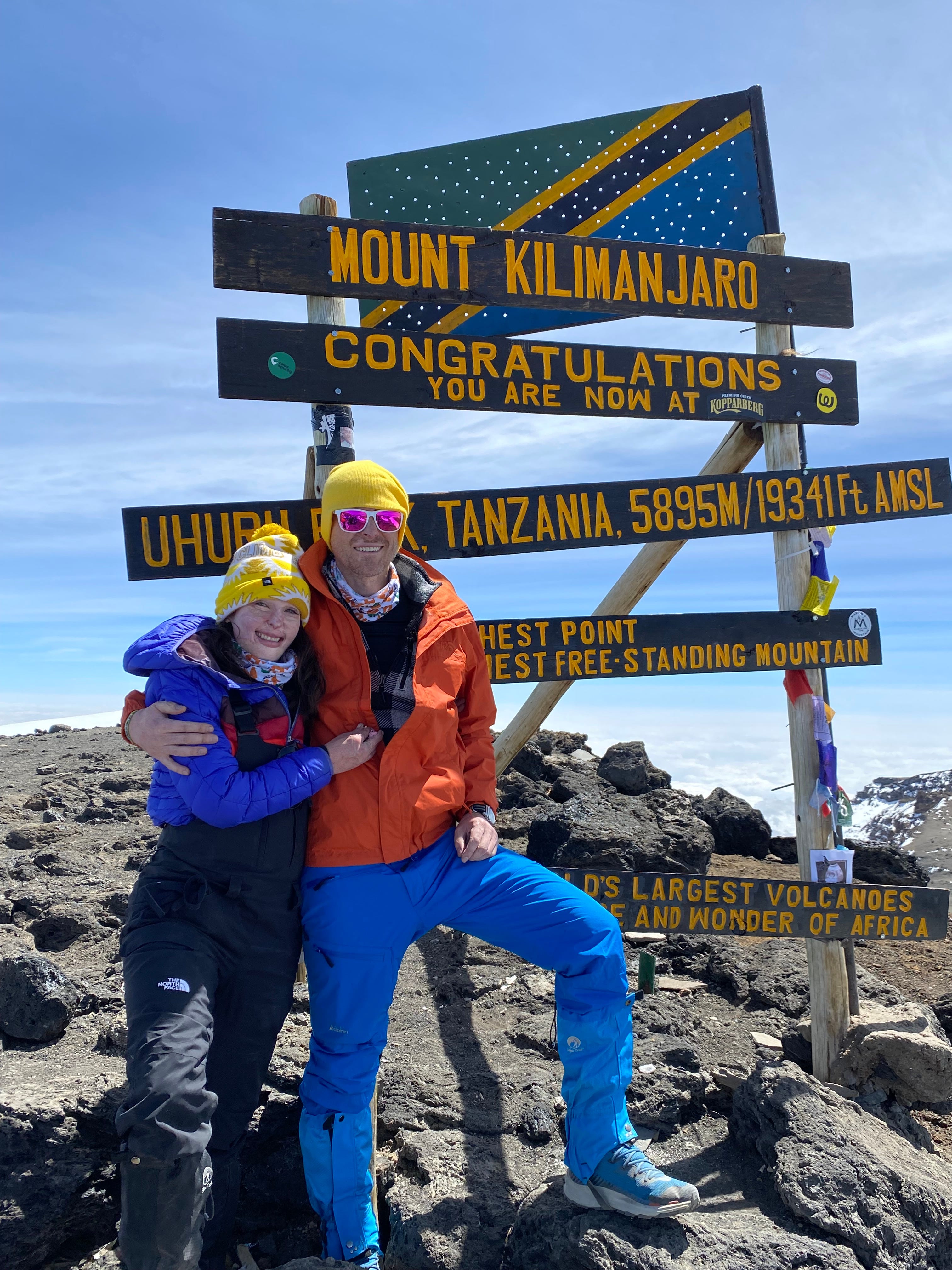 Stephanie And Christian Nielson stand next to the trail marker for Uhuru Peak.