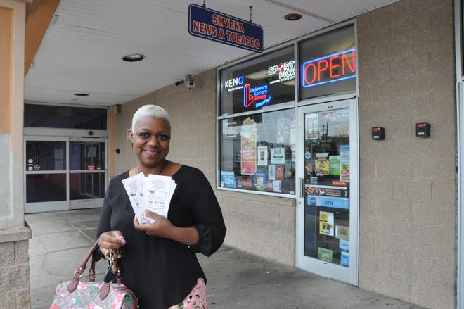 Rebekah McDonald of Clayton displays the 11 Mega Millions tickets she bought Friday morning at Smyrna News & Tobacco on Glenwood Avenue in Smyrna.