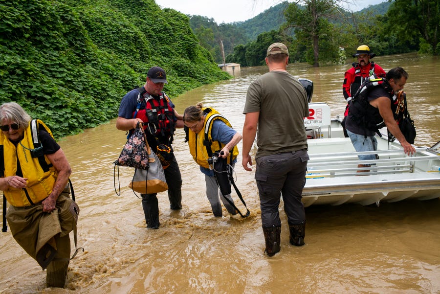 Members of a rescue team assist a family out of a boat on July 28, 2022 in Quicksand, Kentucky.