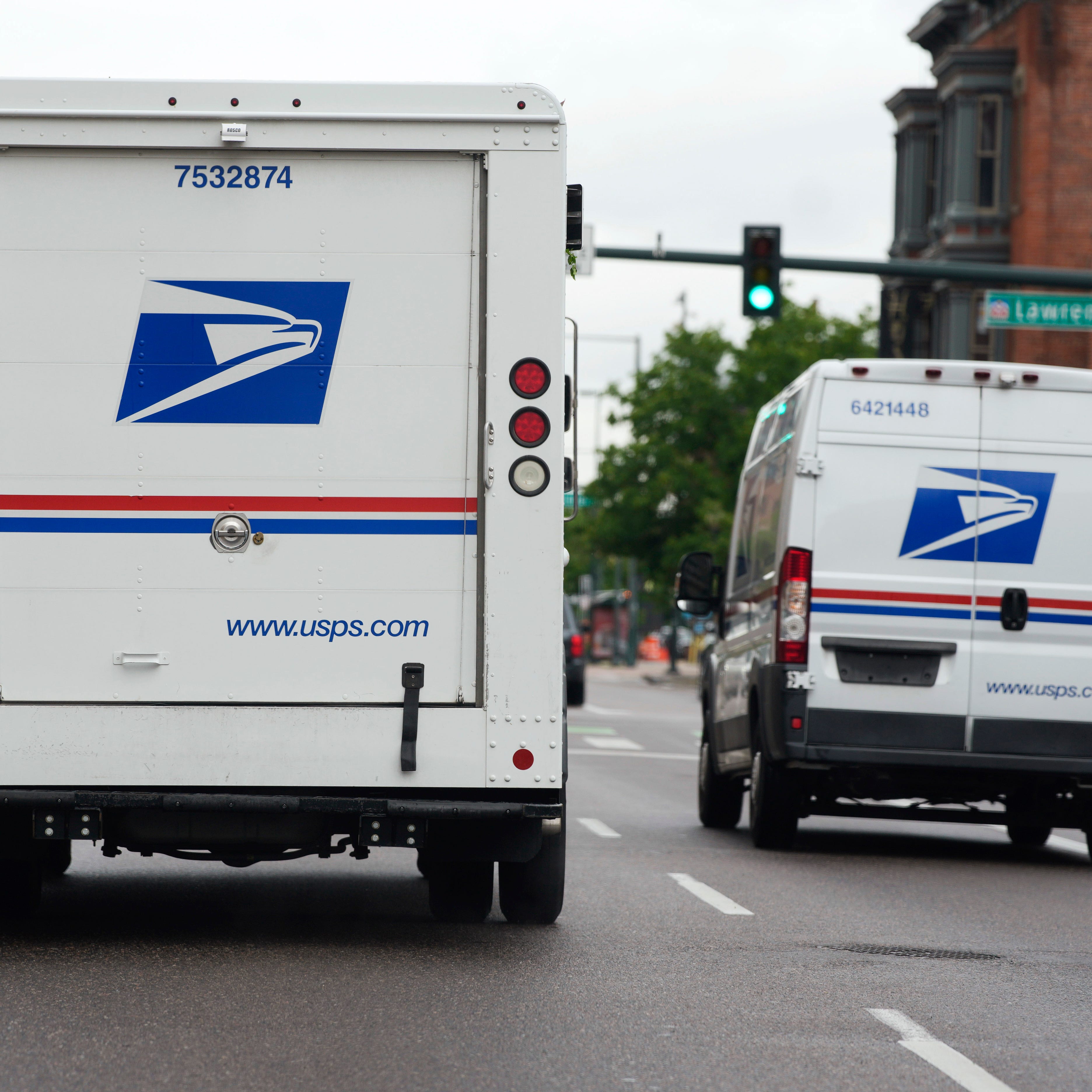 A USPS logo adorns the back doors of United States Postal Service delivery vehicles as they proceed westbound along 20th Street from Stout Street and the main post office in downtown Denver, Wednesday, June 1, 2022. USPS is creating a division to handle election mail issues as part of an effort to ensure swift and secure delivery of ballots for the 2022 midterm election, officials said Wednesday, July 27, 2022.