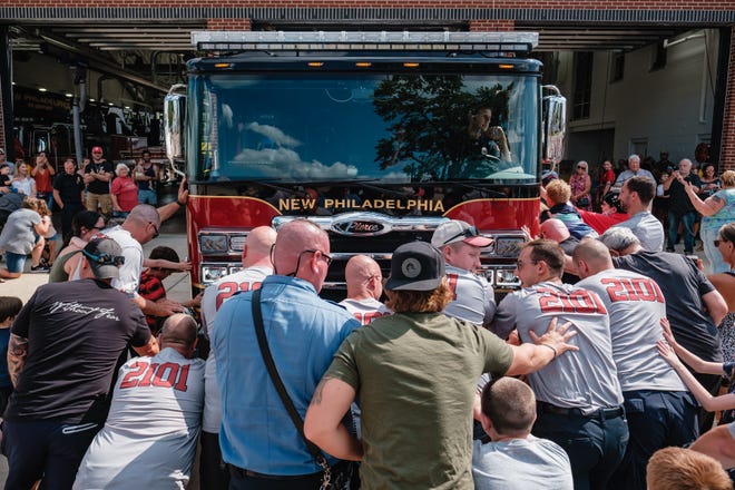 New Philadelphia firefighters, family, and friends participate in the push-in ceremony for the New Philadelphia Fire Department's new engine, 2101, Saturday, July 30 in New Philadelphia.
