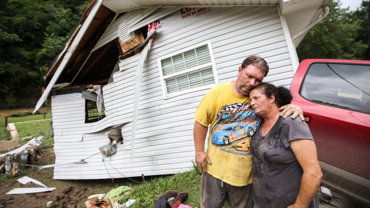 Reggie Ritchie comforts wife Della as they pause while clearing out their destroyed manufactured Fisty, Ky. home destroyed by the flooding from Troublesome Creek behind them. July 29, 2022