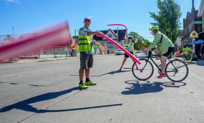 A man who didn't want to be identified, left, and Sarah Milnar direct cyclist traffic with noodles during the Riverwest 24 bicycle race in Milwaukee's Riverwest neighborhood. "The neighborhood comes alive for 24 hours," Milnar said. "I live in Minneapolis now, but come back. It is amazing that this is all volunteer driven."