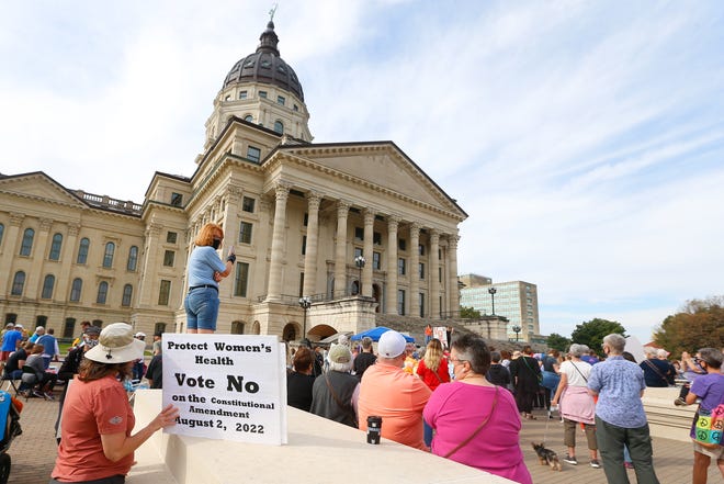A women holds a sign asking voters to vote no on an amendment to the Kansas Constitution regarding abortion during a National Women's March.