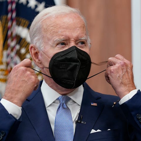 FILE - President Joe Biden removes his face mask a