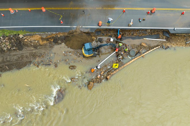 Volunteers and city workers attempt to reconnect the water supply to a nursing home in Elkhorn City, Ky., on Friday, July 29, 2022.  The pipe, along with part of KY-197, washed away yesterday when the Russell Fork flooded.  (Ryan C. Hermens/Lexington Herald-Leader via AP)