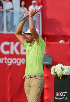 Tony Finau lifts the Rocket Mortgage Classic trophy in joy after winning at the Detroit Golf Club in Detroit on Sunday, July 31, 2022.