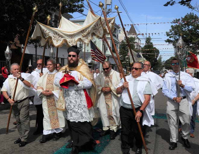 Rev. Christopher Peschel, pastor of Our Lady of Mount Carmel Parish in New Bedford, carries the monstrance during the annual feast Procession through the neighborhood July 31.