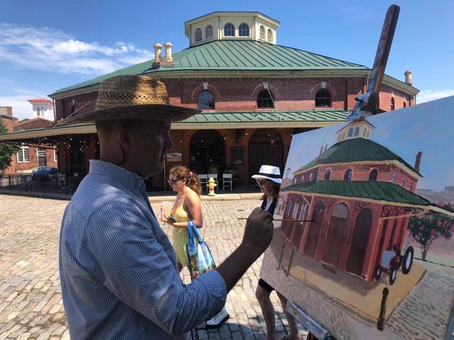 N.C. native Artist Mark Brown paints the iconic Farmers Market building in Old Towne Petersburg on Saturday, July 30. Croaker's Spot restaurant serves diners in the octagonal-shaped space.