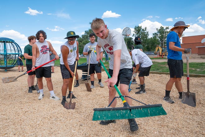Pueblo County High School football players spread mulch in a playground at South Mesa Elementary School on Tuesday.