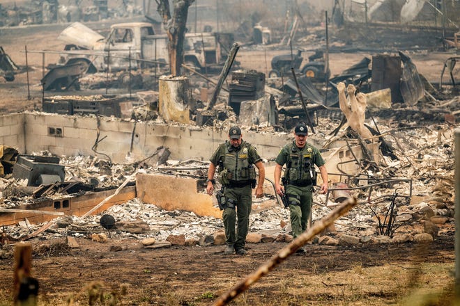 Sheriff's deputies leave a home where a McKinney Fire victim was found on Monday, Aug. 1, 2022, in Klamath National Forest, Calif. (AP Photo/Noah Berger)