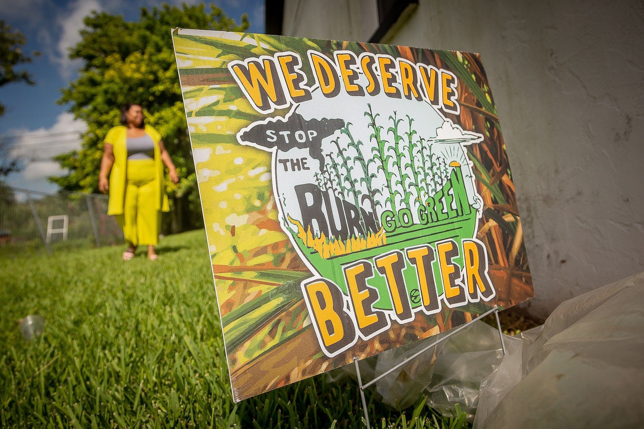 Kina Phillips has a sign protesting cane burning in the front yard of her home. She says she has given up hope that Agriculture Secretary and gubernatorial candidate Nikki Fried will make changes that spare her community from the effects of the practice.