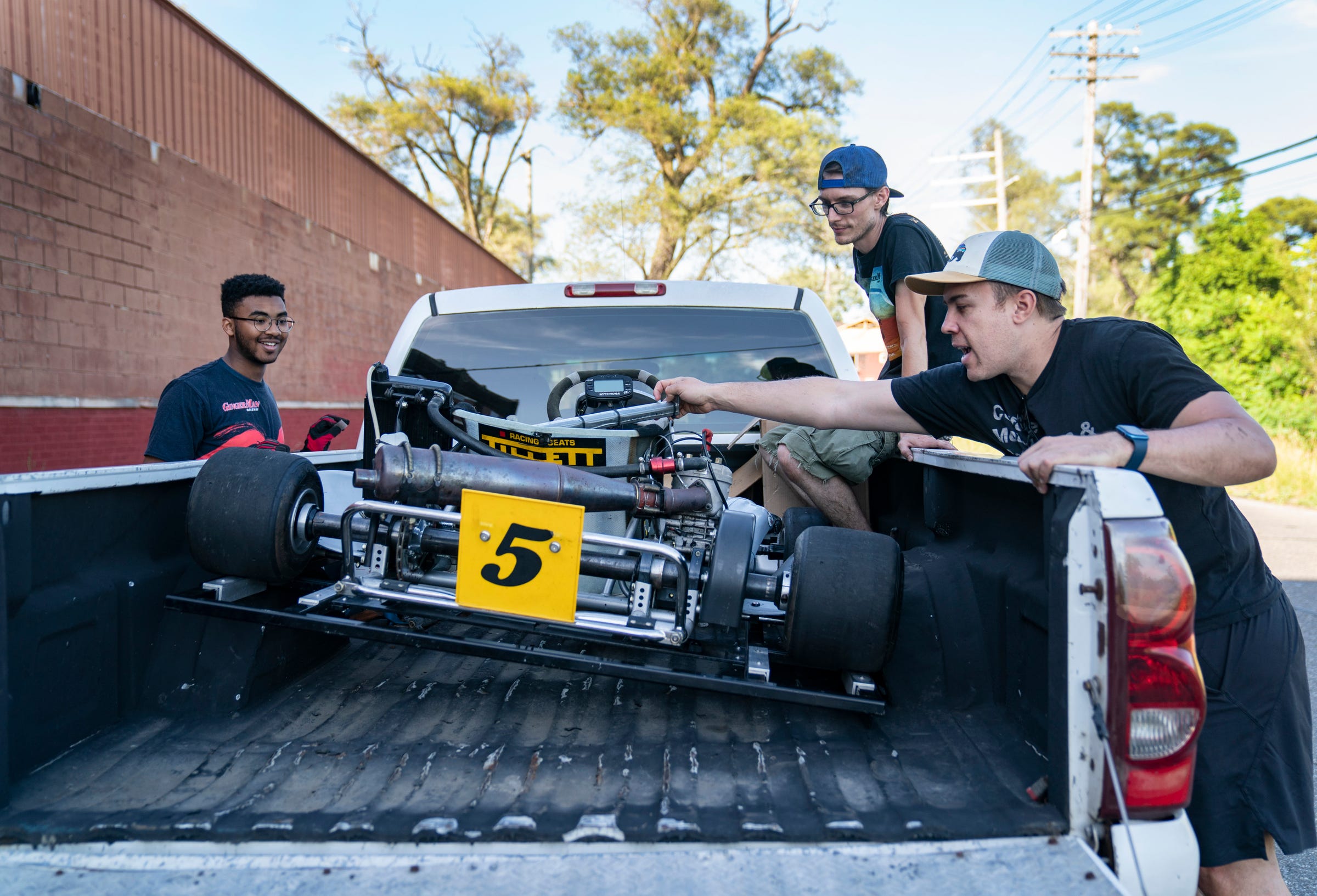 Detroit Student Race Team member Noah Christian, 17, of Detroit, left, works to unload a go kart with mentor Shane O'Connor, 31, and  team founder Andy Didorosi Wednesday, June 22, 2022 at their shop location in Detroit.