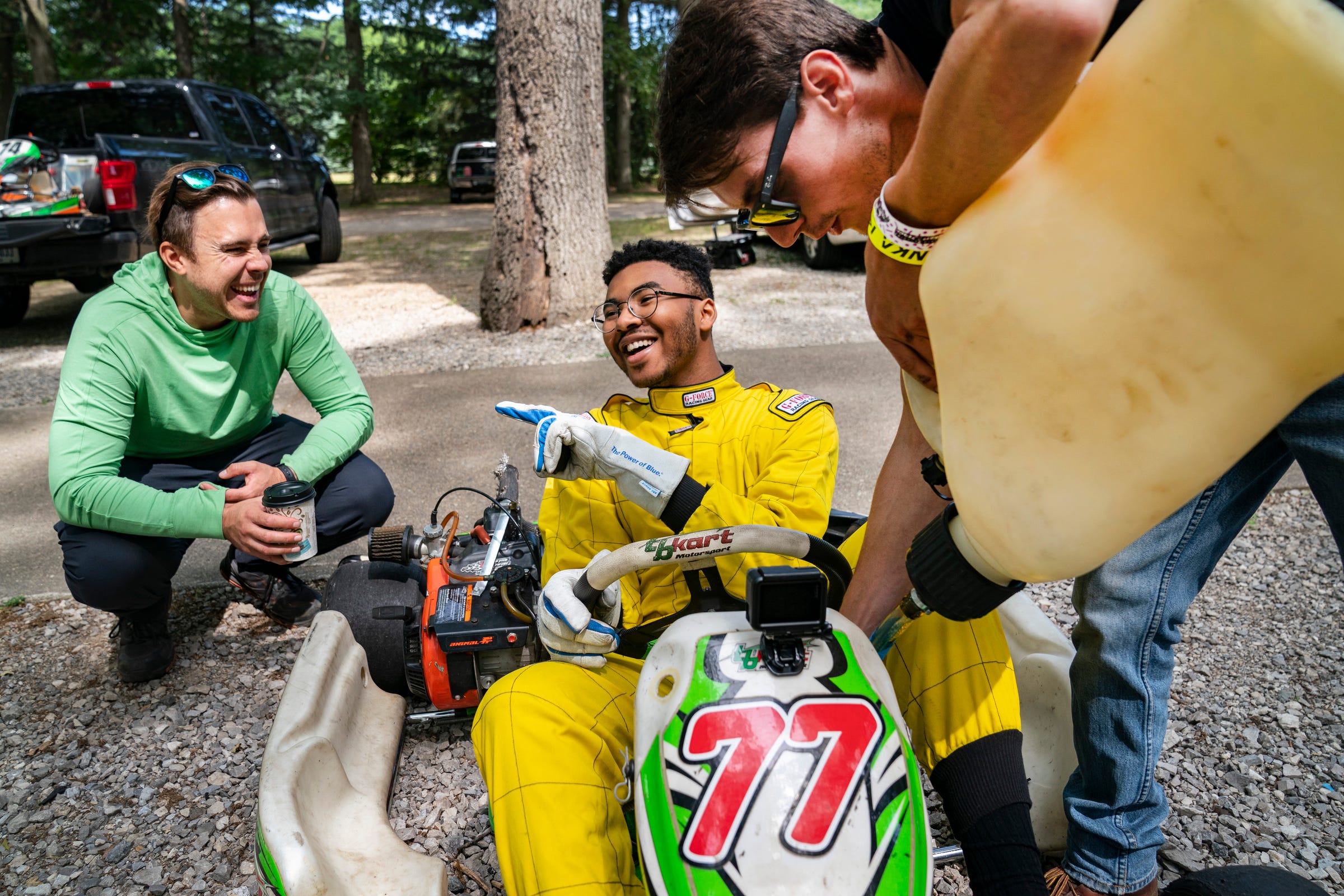 Andy Didorosi, left, of Detroit, and founder of the Detroit Student Race Team, talks strategy with student Noah Christian, 17, of Detroit, center, as team mentor Shane O'Connor gasses up the team go-kart before practice runs at the East Lansing Kart Track on Saturday July, 2, 2022.