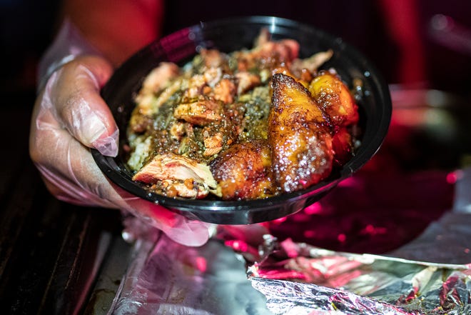 Chef D (Dionte Braxton) shows a plate he made with sweet and spicy plantain, coconut rice and lemon pepper jerk chicken during Jerk X Jollof at Delmar in Detroit on July 21, 2022.