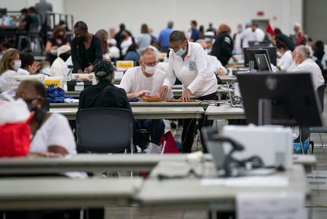 An election worker and his supervisor count absentee ballots inside Hall E of Huntington Place in downtown Detroit on August 2, 2022.