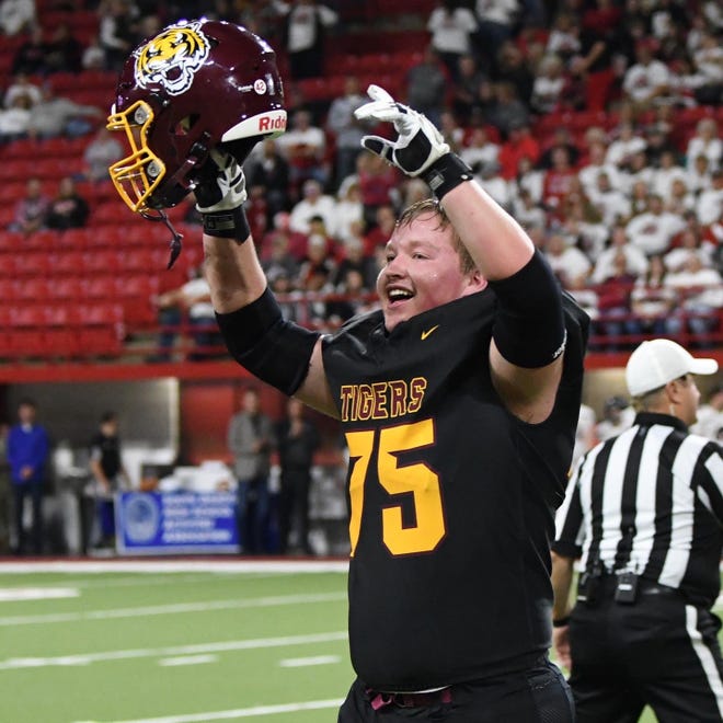 Former Harrisburg offensive lineman Mason Jacobson holds his helmet above his head in celebration during the Tigers 11AAA championship win at the DakotaDome.