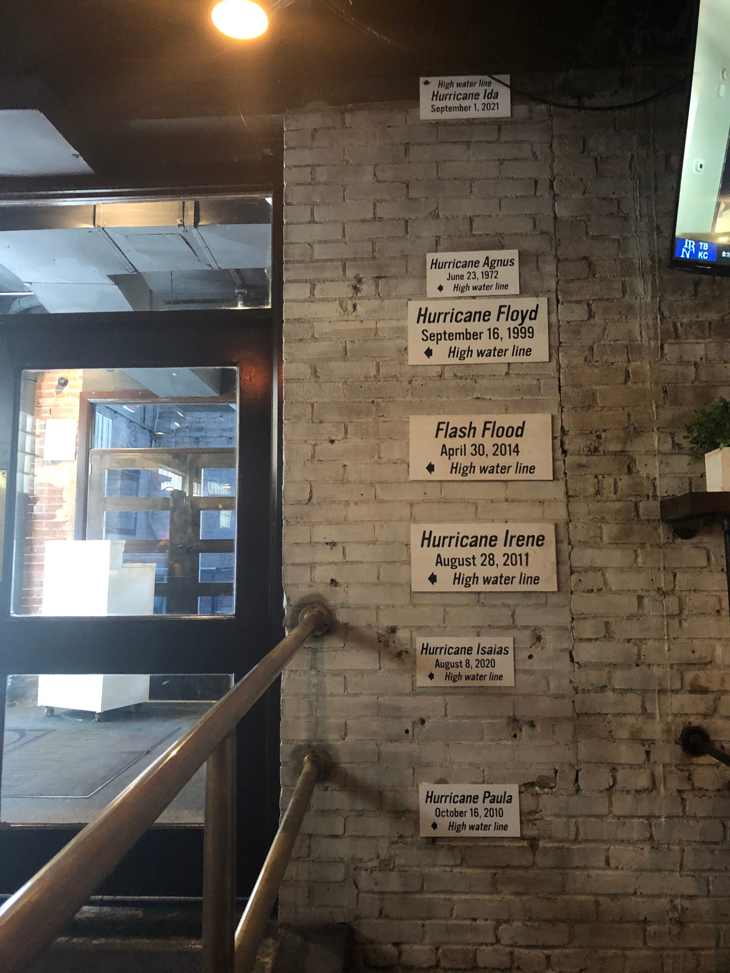 Hurricane Irene, Hurricane Isaias, an unnamed flash flood in 2014, Agnes from 1972 — various high-water lines climb the wall in Manayunk Brewing Restaurant and Bar, in Philadelphia, on July 22, 2020. Black arrows mark each floodwater peak.