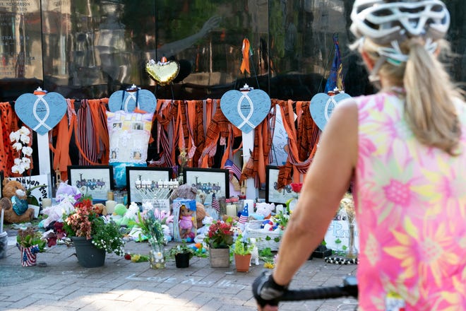 A woman stops by a memorial for the victims of the mass shooting at a Fourth of July parade in downtown Highland Park, Illinois, on Aug. 2, 2022.