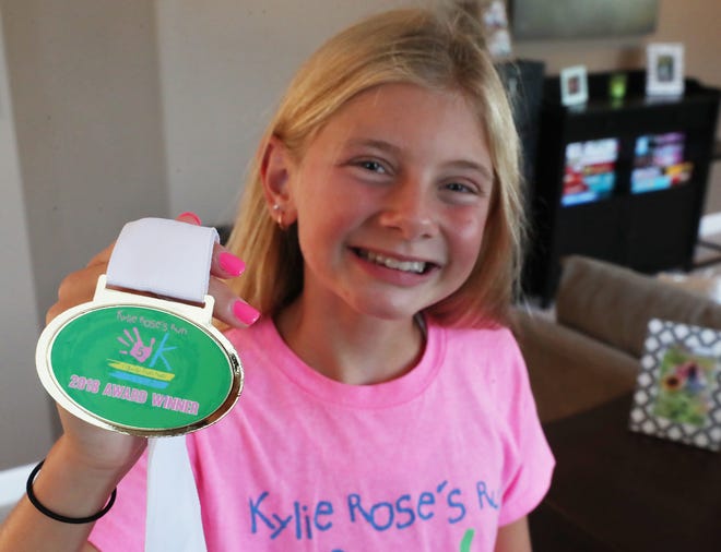 Kylie Jacobs, 13, holds a medal from the 2018 Kylie Rose's 5K Run at her family's home on Wednesday in Copley.