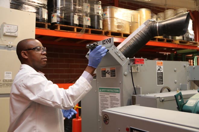 Ikenna Nlebedim, scientist at Ames National Laboratory and the Critical Materials Institute, loads hard drives into a specialized shredder that can quickly turn obsolete technologies into a mound of pulverized scrap from which scientists can recover and reuse rare-earth metals.