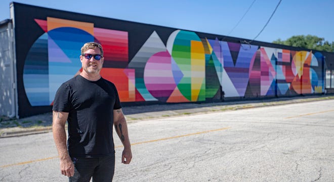 Brett Whitacre poses in front of his mural on Friday, Aug. 5, 2022, in Loves Park.
