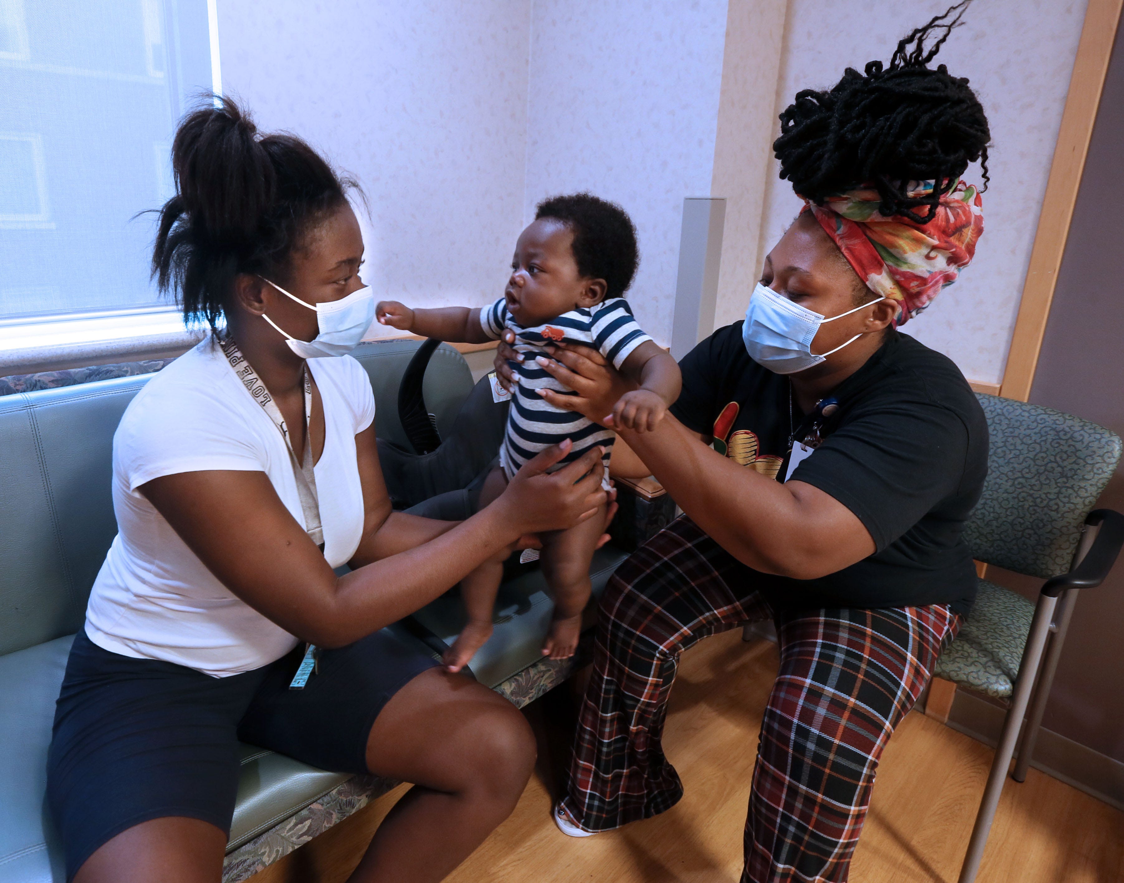 Santana Grady, right, a community health worker, hands 5-month-old Veon Jackson to his mother, Jermesha Farmer, while at a newborn checkup at Ascension SE Wisconsin Hospital - St. Joseph Campus, Milwaukee.
