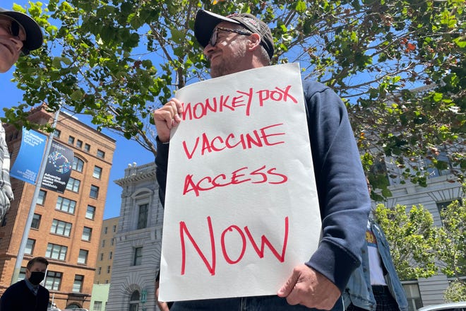 A man holds a sign urging increased access to the monkeypox vaccine during a protest in San Francisco, July 18, 2022.