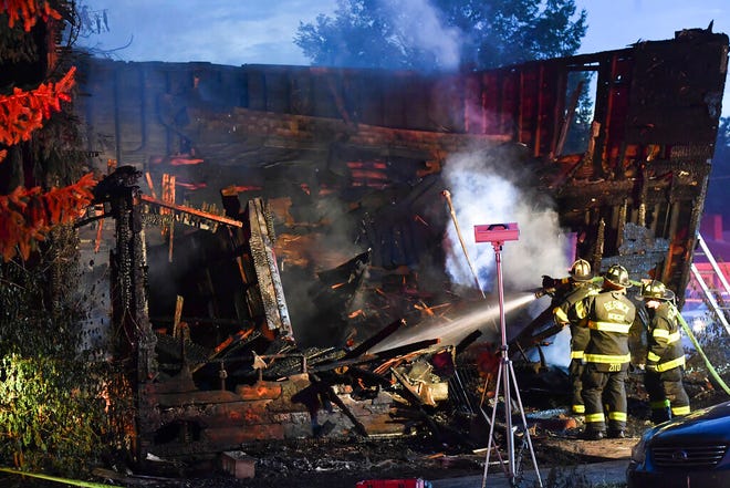 Firefighters work on hot spots in the front section of the home which collapsed during an early morning fatal fire on First Street in Nescopeck, Pa., Friday, Aug. 5, 2022. The fire was reported around 2:30 a.m. The cause of the fire remains under investigation. (Jimmy May/Bloomsburg Press Enterprise via AP)