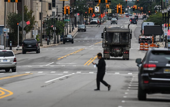 A man crosses the street as a southbound vehicle is seen in the wrong lane in a section of the newly-changed two-way street along North Capitol Avenue near Shiawassee Street seen Monday, Aug. 8, 2022.