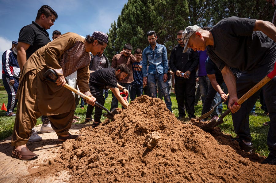 People spread dirt over Aftab Hussein's grave at Fairview Memorial Park in Albuquerque, N.M., where a funeral service was held for Hussein, 41, and Muhammad Afzaal Hussain, 27, at the Islamic Center of New Mexico. Both Muslim men were shot and killed near their homes six days apart.