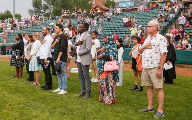 Fifteen new U.S. Citizens say the pledge of allegiance after taking the Oath of Allegiance ahead of the RedHawks game on Tuesday, Aug. 2, 2022, at Newman Outdoor Field in Fargo