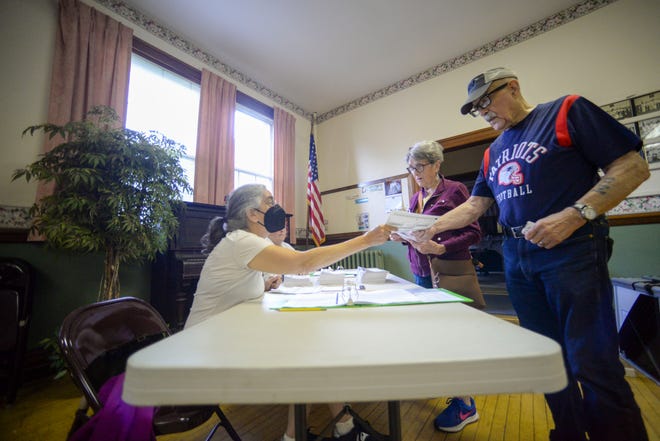 Leslie Goldman, a poll worker at the Rockingham Polling Station in Bellows Falls, gives a ballot to Don and Maggie Nowers, of Bellows Falls, to vote in the state's primary election, Tuesday, Aug. 9, 2022.