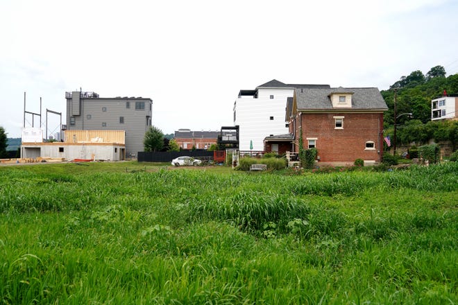 A view of a vacant lot as new construction continues in the background alongside existing homes, Tuesday, Aug. 2, 2022, in the East End neighborhood of Cincinnati. Some of the new homes being built in the neighborhood are on vacant lots.