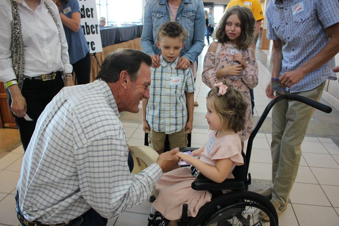 South Dakota Lt. Gov. Larry Rhoden chats with a child, Kendyl, at the Sturgis Rally. Kendyl was born with spina bifida.
