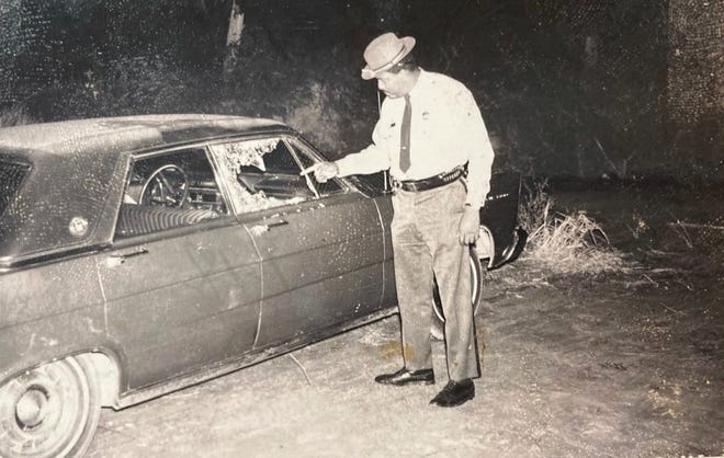 Deputy Eugene Seigler Jr. points to bullet holes in a car on Lovers Lane in January 1971.