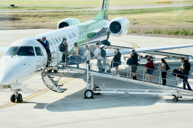 Passengers walk up a ramp to board a Denver Air Connection jet in preparation for a flight to Chicago. The flight was the first to leave Watertown’s new airport terminal.