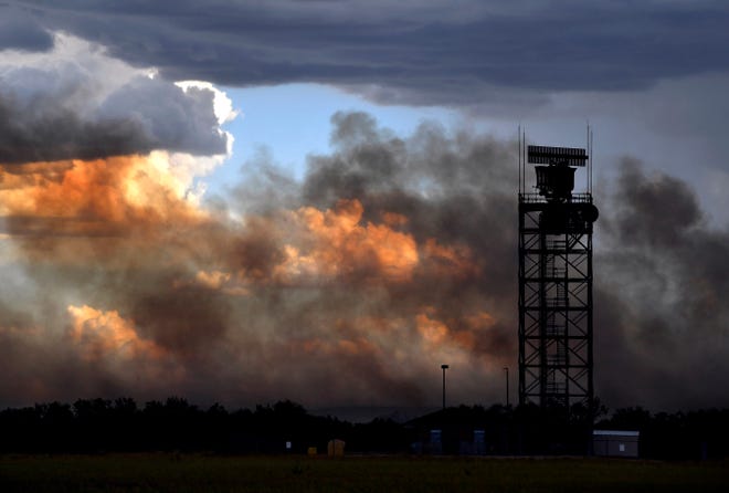 Smoke from a grassfire drifts past the Abilene Regional Airport on State Highway 36, coloring the clouds in the distance orange, during Tuesday's storm.