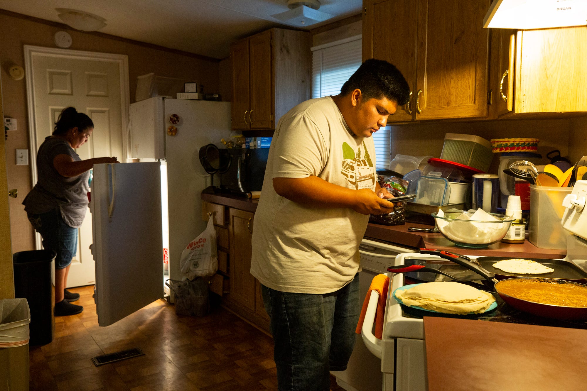 Carlos Medina ayuda a su madre, Janneth Gonzalez, a preparar una comida para la familia en su casa en Lake Dallas, Texas.