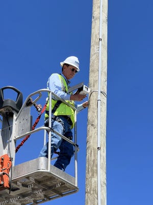 A contractor installs an air monitor on a utility pole in Port Fourchon to measure greenhouse gas emissions and other air pollutants in real time.