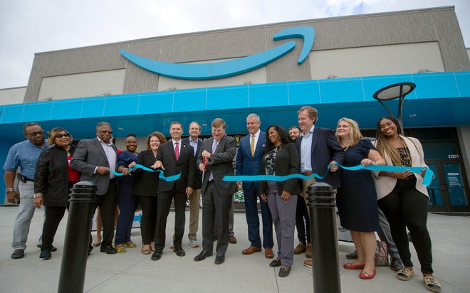 Gov. Tate Reeves, center, and other dignitaries join Amazon in celebrating the grand opening of JAN1, the Amazon Fulfillment Center in Canton Miss., during a ribbon cutting at the facitity Thursday, Aug. 11, 2022. The facility is the first Amazon robotics sort center in the state.