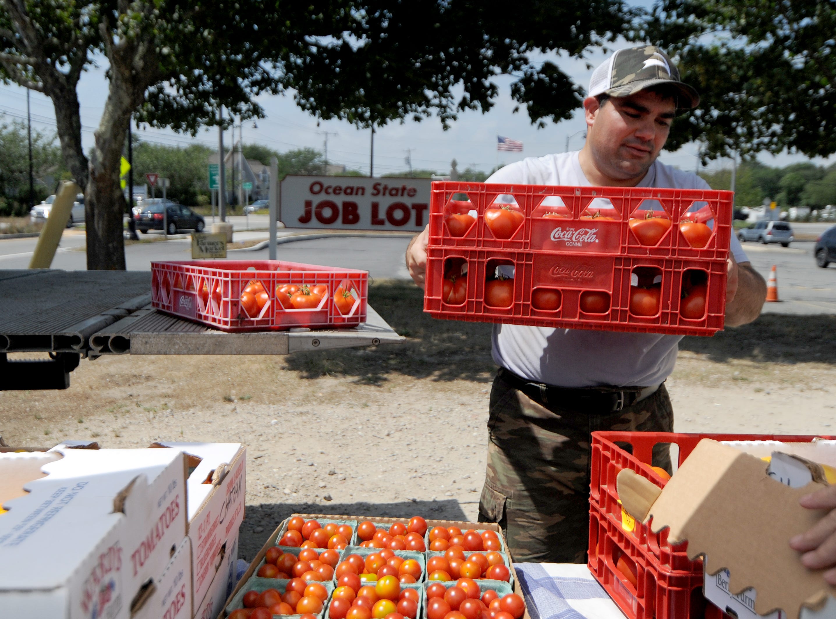 Program participant Joseph Capello helps to unload trays of tomatoes and other vegetables brought to the Chatham Farmers Market Tuesday, Aug. 9, 2022.
