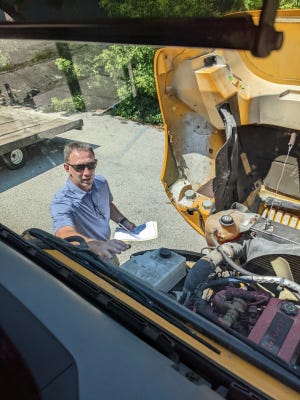 Pewaukee High School athletic director Jeff Behrens does a check of a school bus engine as part of training for his commercial driver's license.