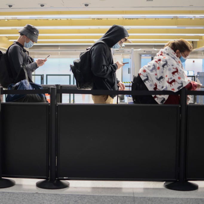 Passengers look at their phones as they wait to walk through a TSA security checkpoint at the Ronald Reagan Washington National Airport on November 24, 2021 in Arlington, Virginia.