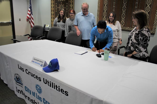 Surrounded by family, new Las Cruces Utilities Intern Jeremiah Avery signs his contract to join the LCU Internship Program next to LCU Director Delilah Walsh.