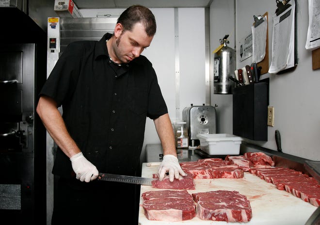 Flashback to 2011: Executive Chef Jamie Steinbrecher cuts a New York strip steak with a butcher knife at Okeechobee Steakhouse, where he was head chef for 13 years.  Steinbrecher is now Executive Chef at He Jupiter's Lewis Steakhouse, a sister restaurant of Okeechobee Steakhouse.
