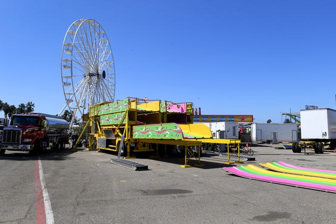 A giant slide sits partially dismantled as workers disassemble rides on the midway at the Ventura County Fairgrounds on Monday, August 15, 2022.